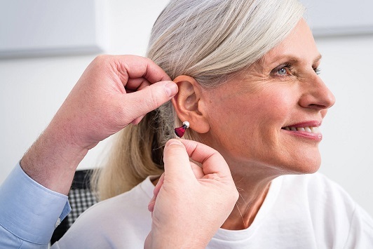 Ältere Frau bekommt modernes Hörgerät angepasst, Hörakustik und Hörhilfe im Alltag.